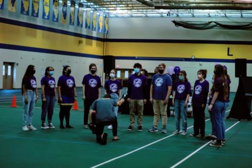 Madrigals performing, conductor kneeling down, holding mic out